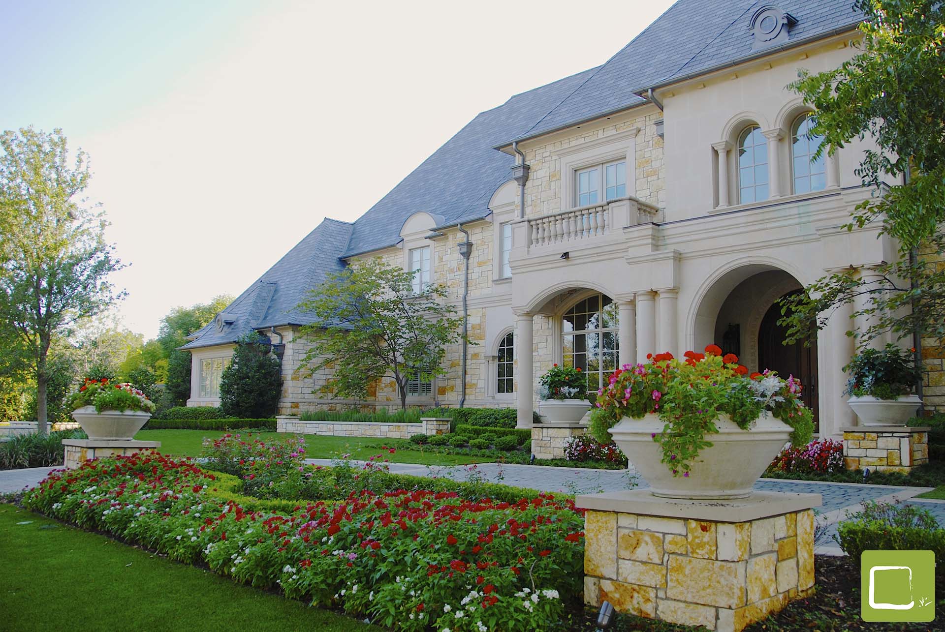 Formal auto court entry with stone planters in Dallas by landscape architect